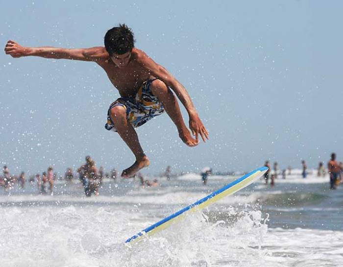 Teenager doing an ollie on a skim board in the water